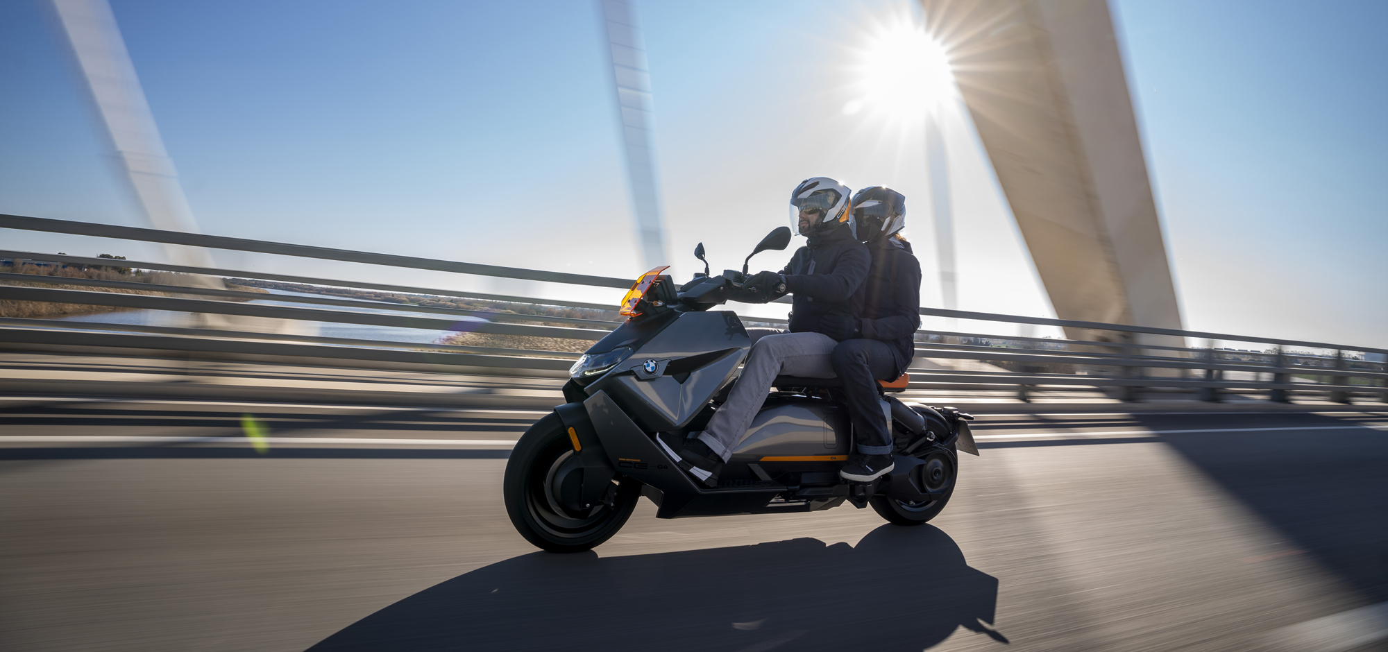 BMW Urban mobility motorcycle with passenger riding across bridge