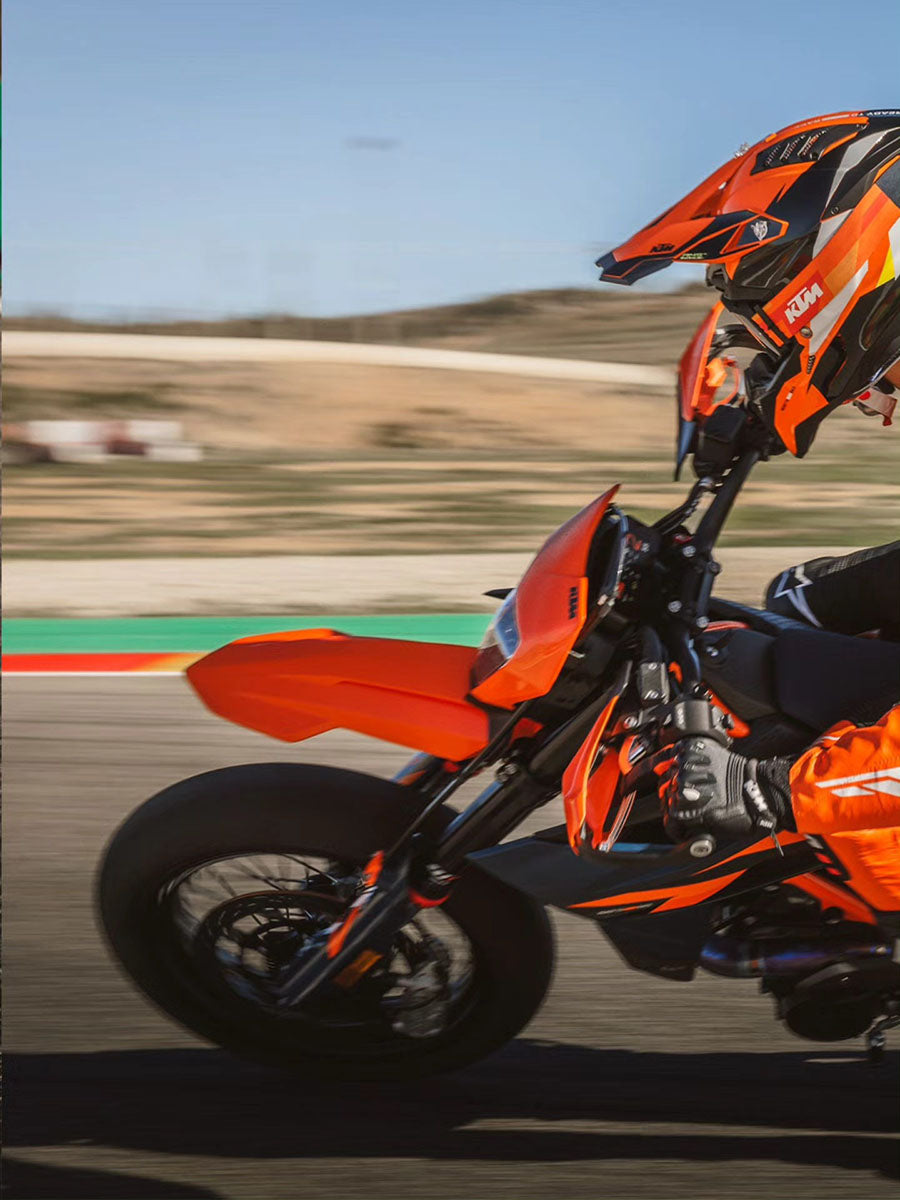Orange KTM motorcycle and helmet on a racetrack with blurred background