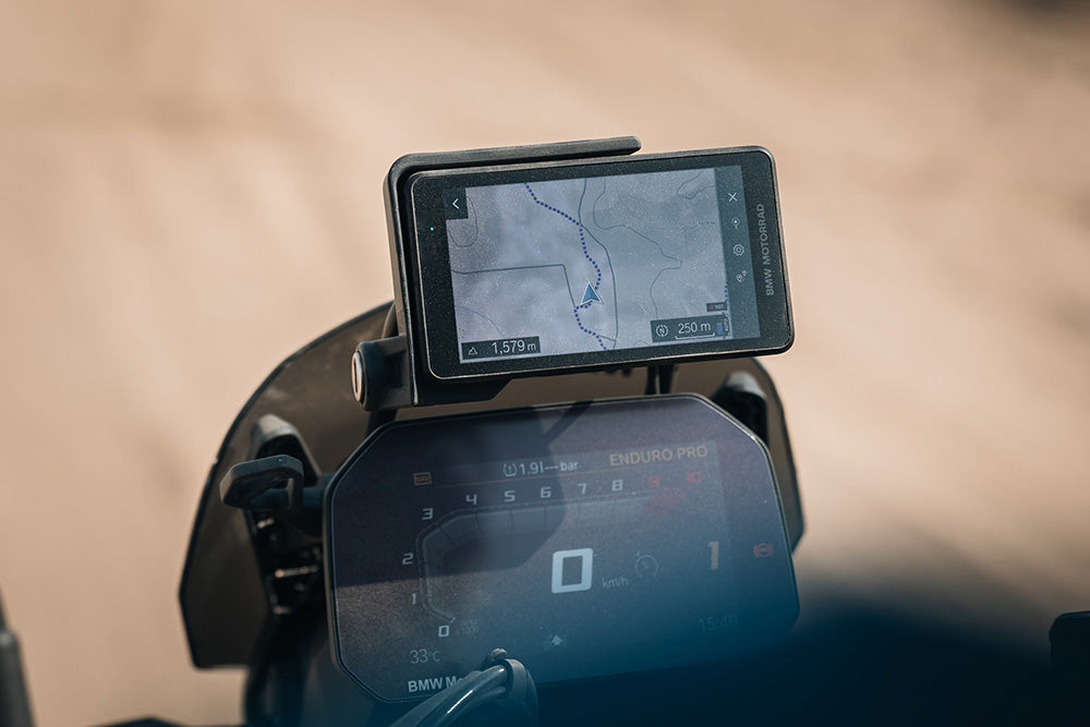 GPS device mounted on a motorcycle dashboard with a blurred background