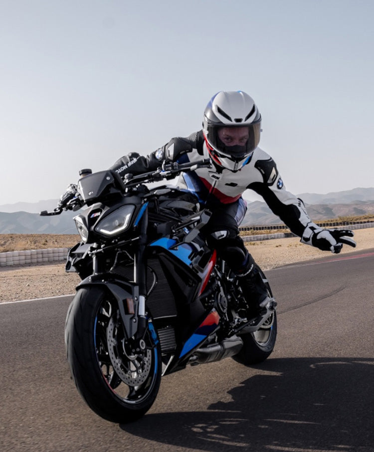 Person riding a motorcycle on a road with mountains in the background