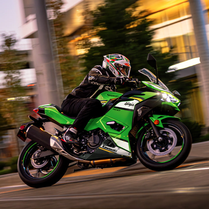 Person riding a green Kawasaki motorcycle on a city street