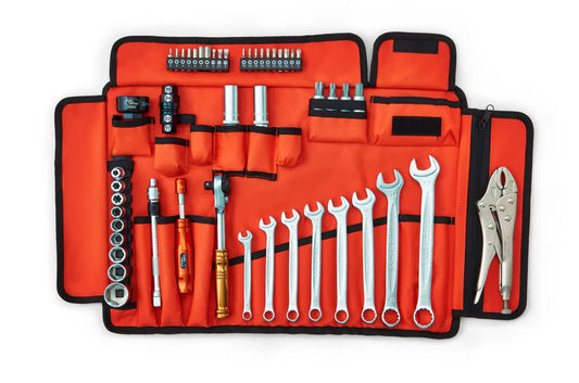 Set of tools in an orange roll-up tool bag on a white background